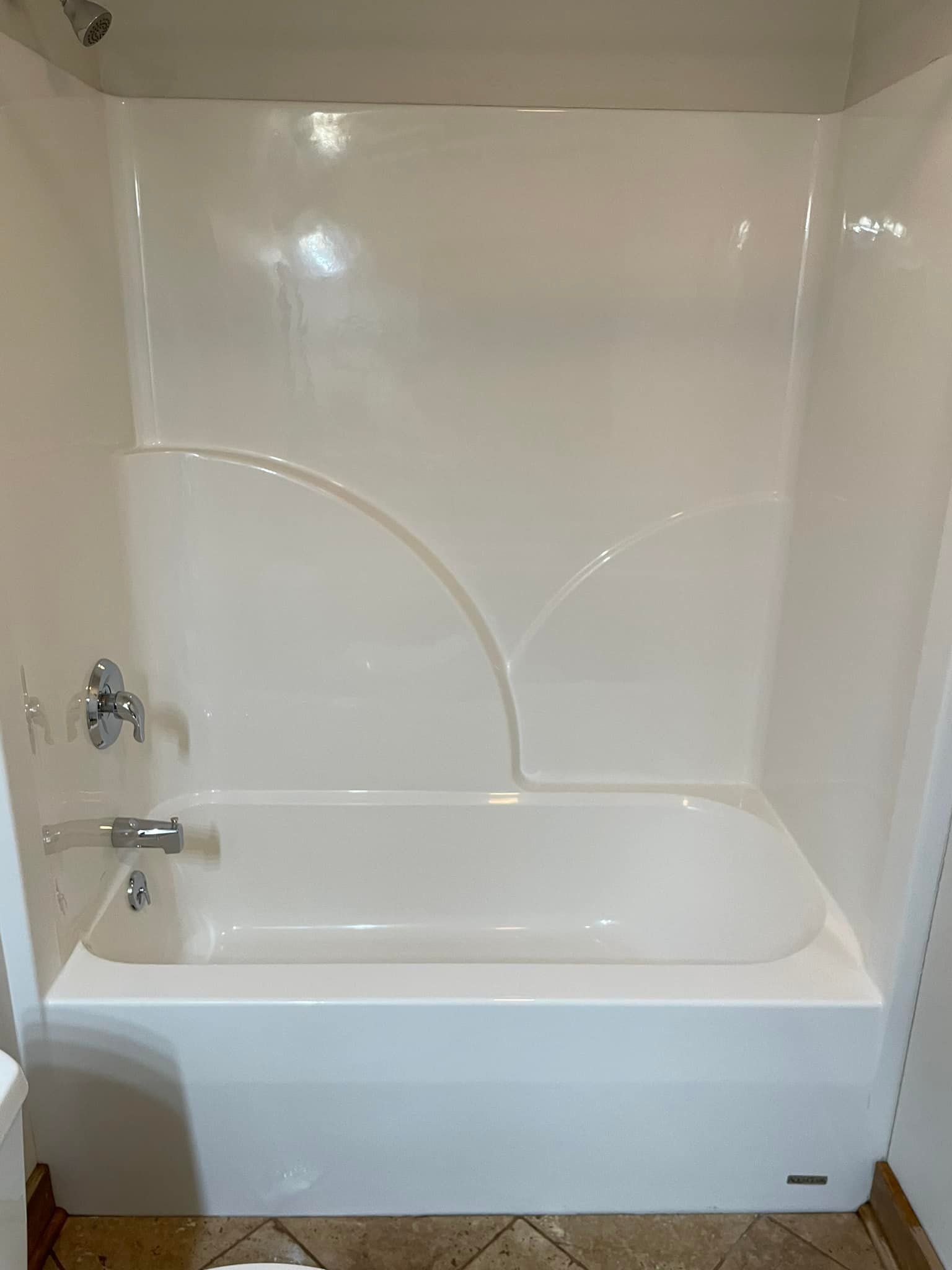 A white bathtub is sitting in a bathroom next to a toilet.