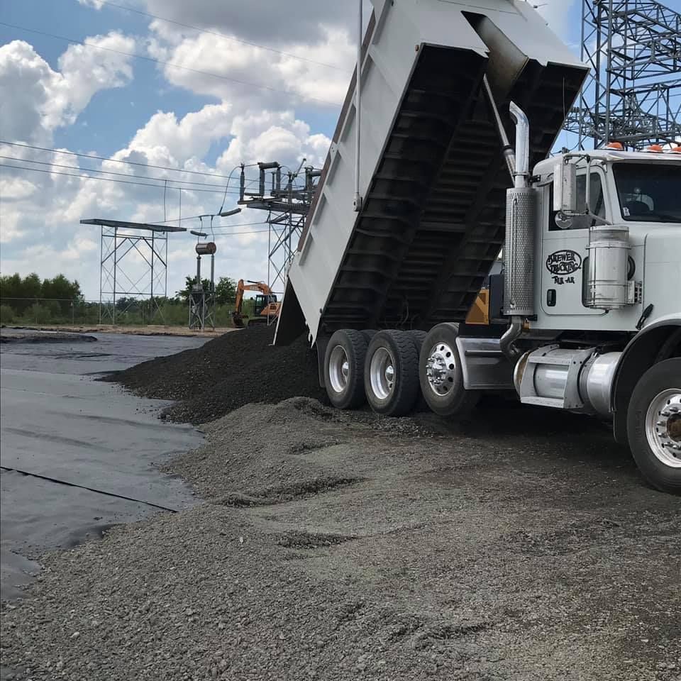 A white dump truck is unloading gravel. A white dump truck is unloading gravel.