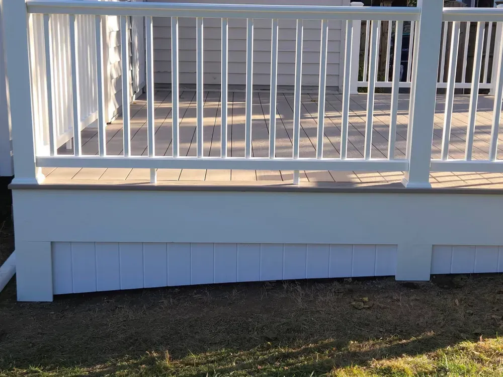 White porch railing above a light blue skirting wall over a grassy yard