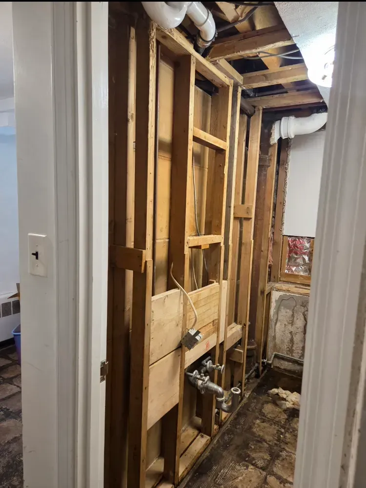Small hallway with worn flooring, white walls, a doorway to another room, and a staircase on the right.