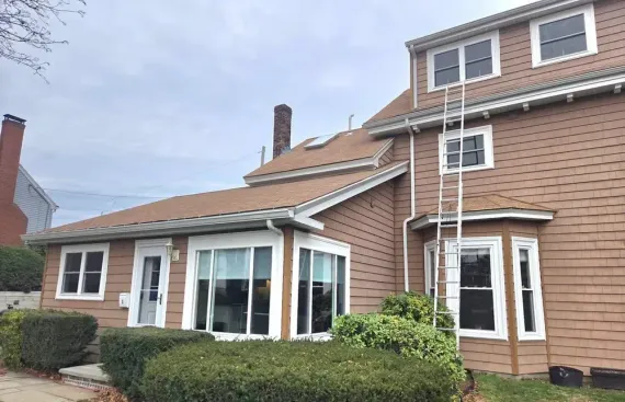 Suburban house with brown siding, white trim, and a screened porch under cloudy skies