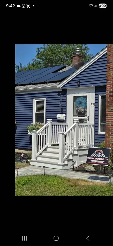 Blue house with white trim, front porch steps, and a small sign in the yard.