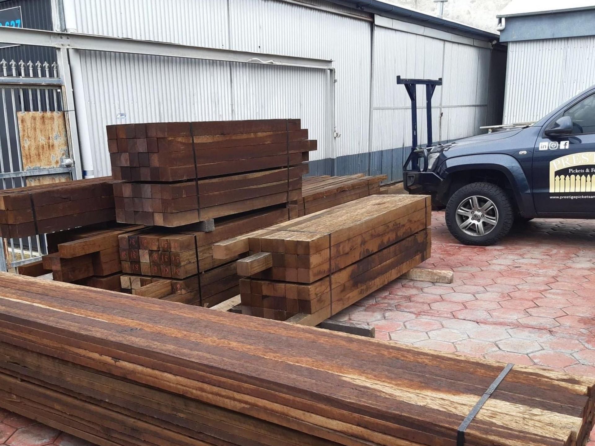 A ute is parked next to a pile of timber fencing materials.