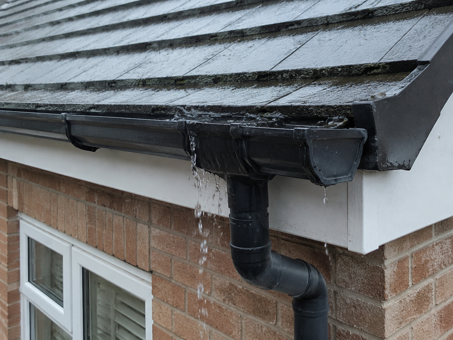 Rainwater overflowing from residential guttering during steady rainfall