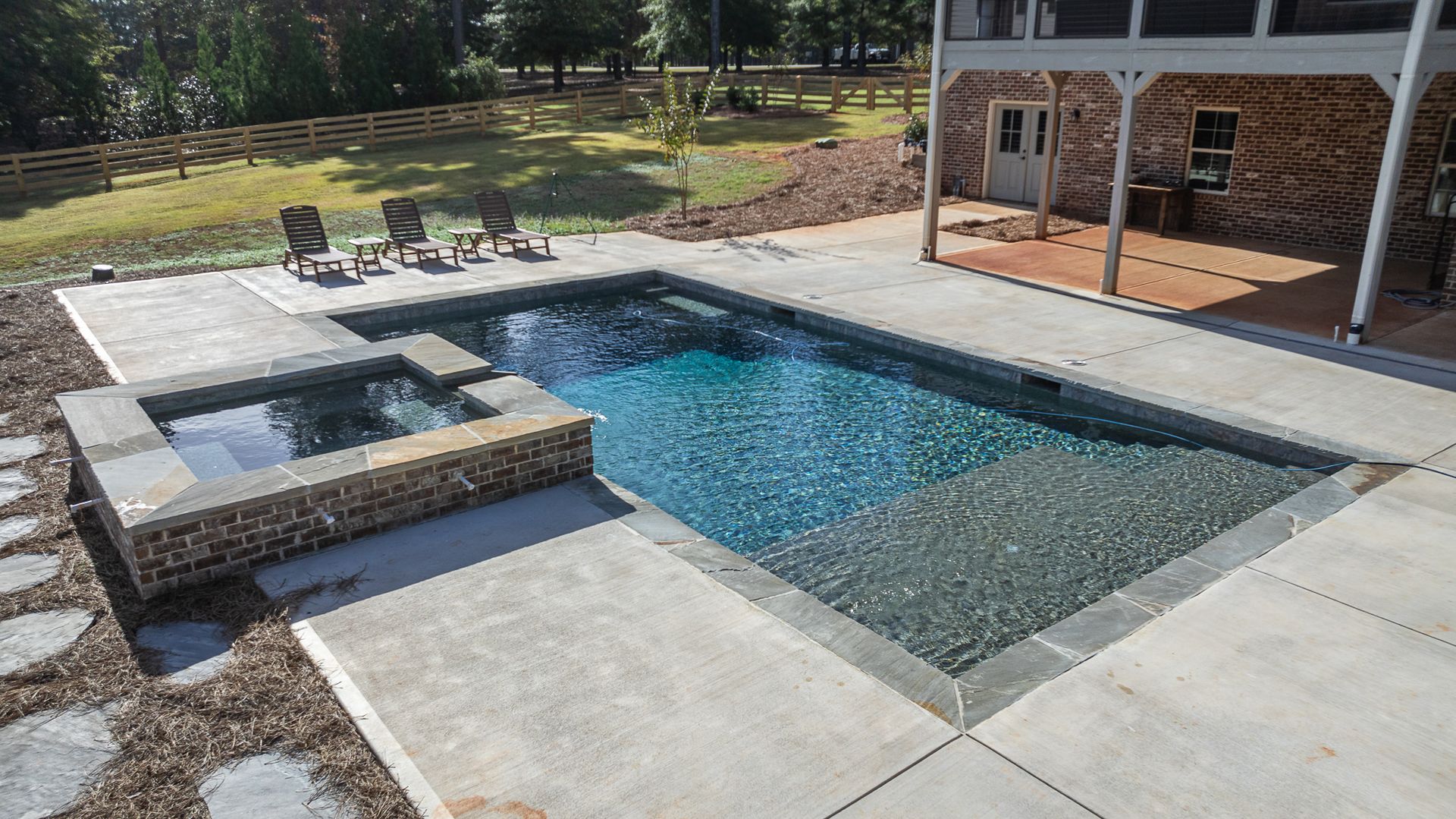 A large swimming pool with a hot tub in the backyard