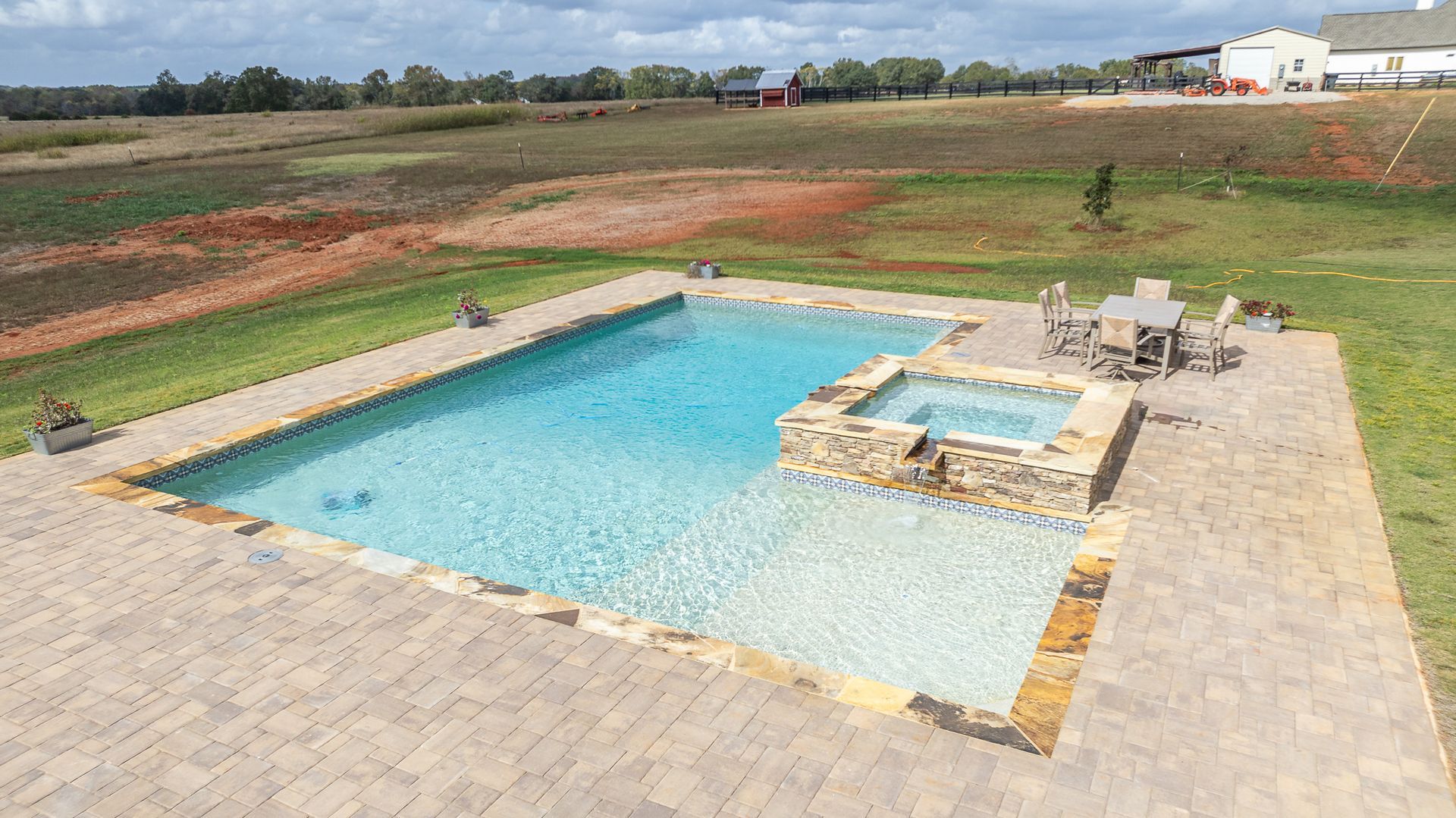 There is a large swimming pool with a hot tub in the middle of it.