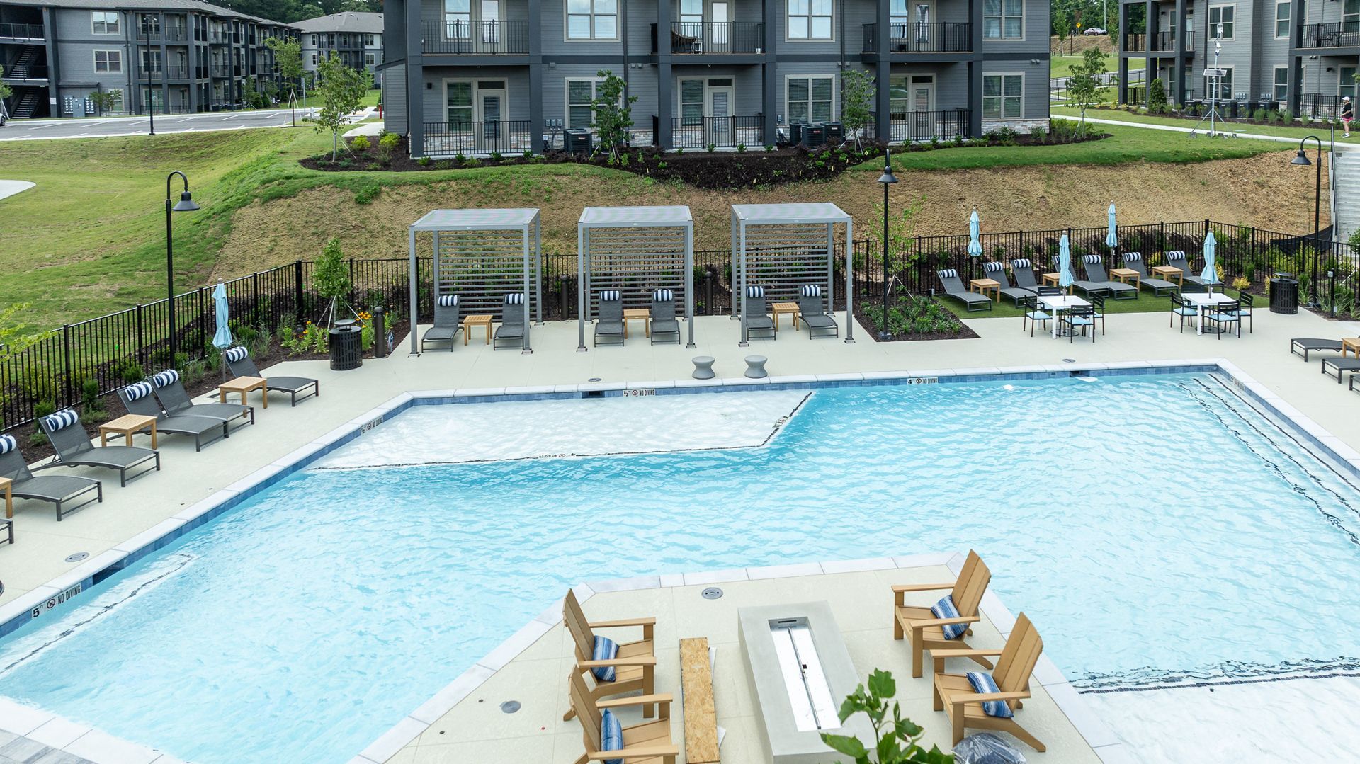 Outdoor resort pool with lounge chairs, cabanas, and apartment buildings in the background