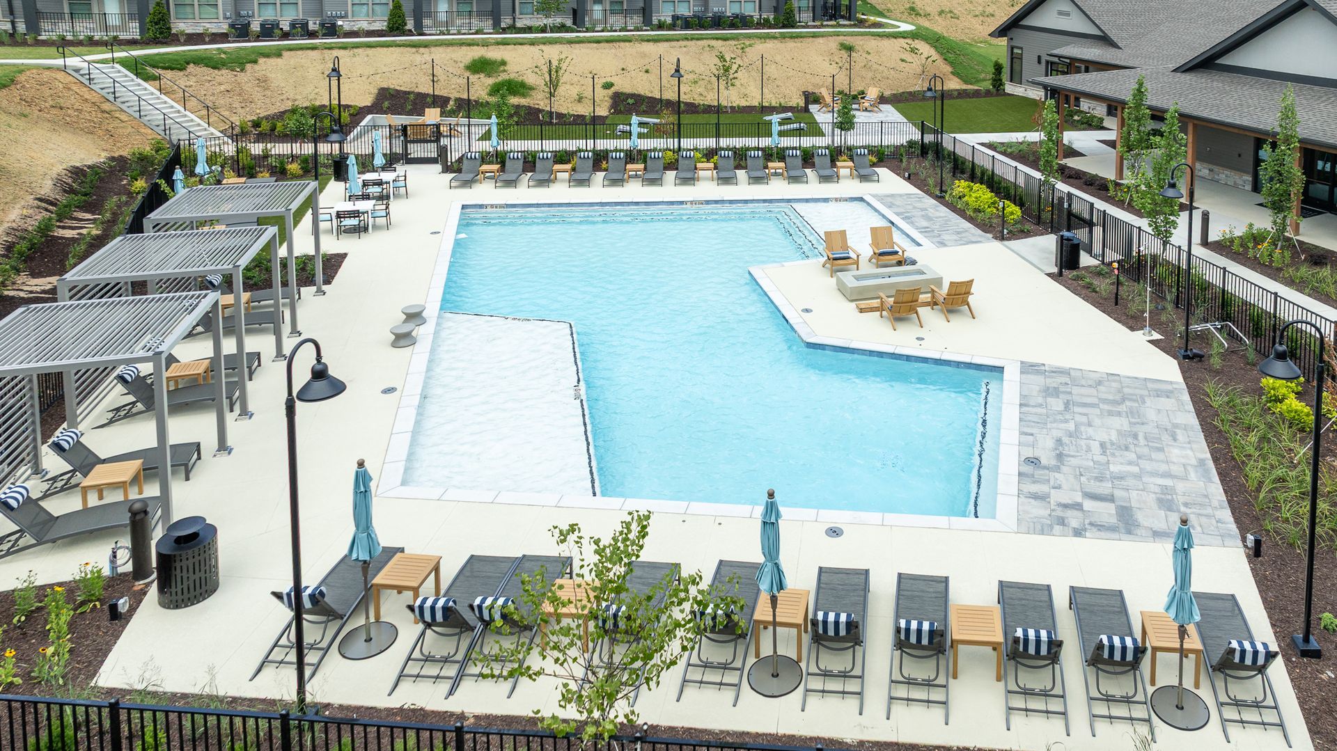 Outdoor resort pool with lounge chairs, umbrellas, and a shallow tanning ledge on a sunny day