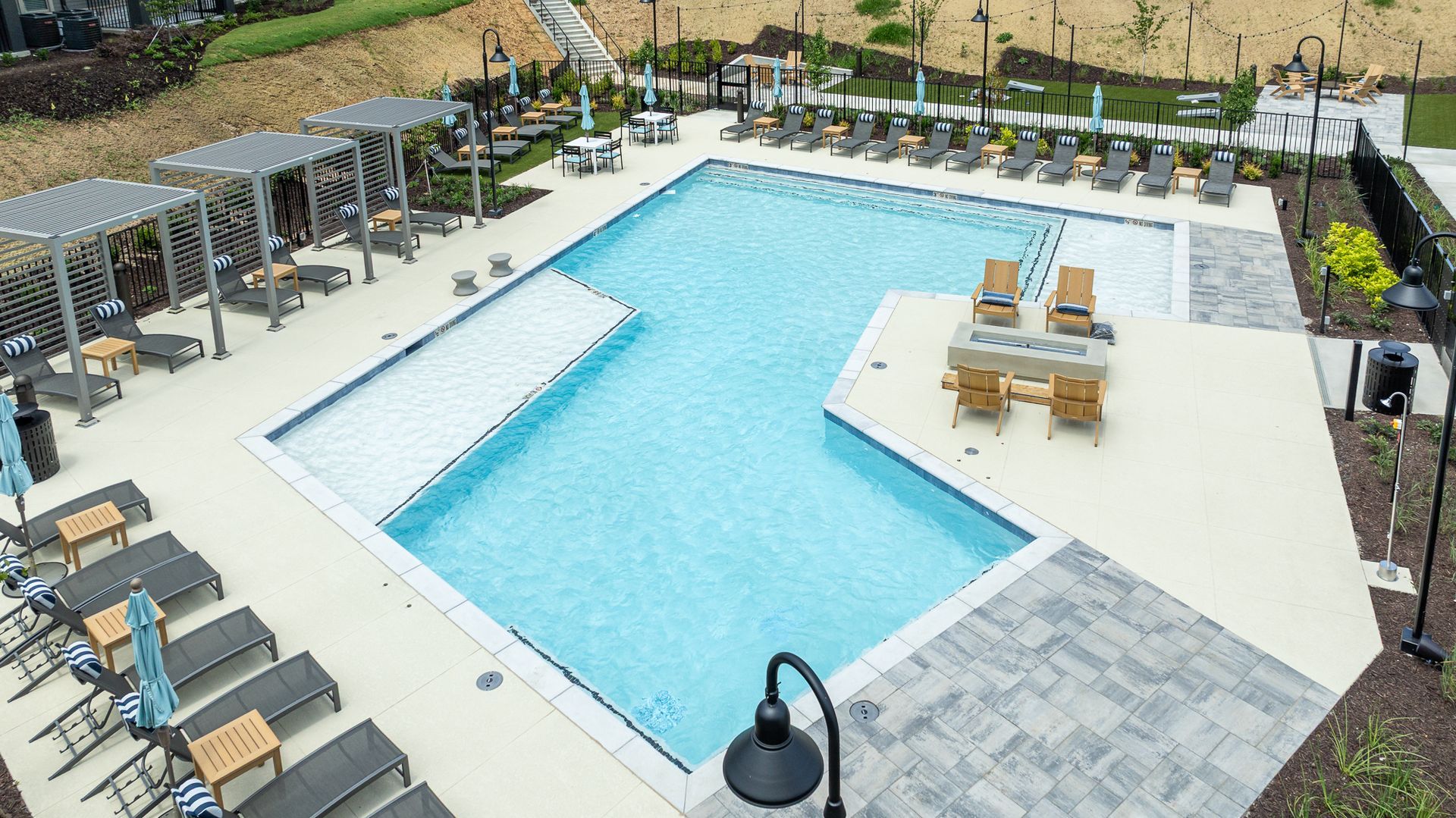 Aerial view of an outdoor swimming pool with lounge chairs and a dining table on a patio.