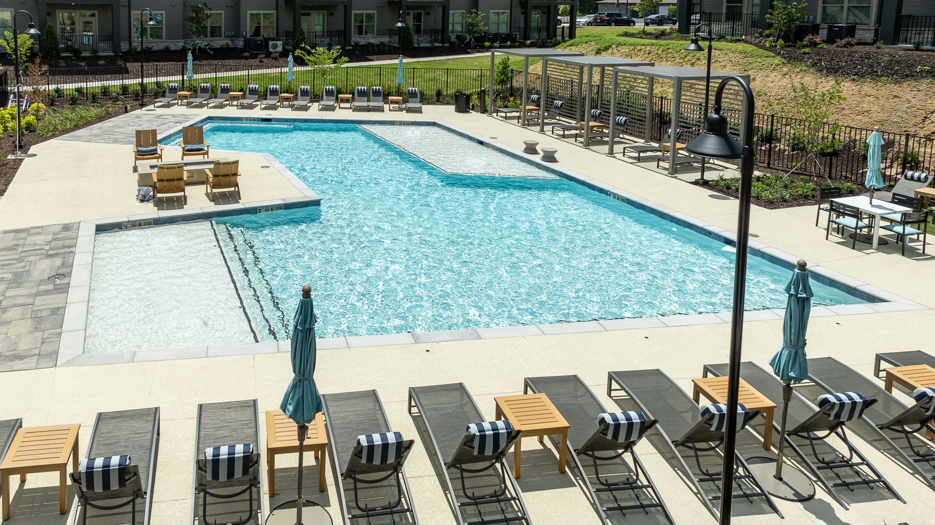 Outdoor swimming pool with lounge chairs, umbrellas, and a small seating area