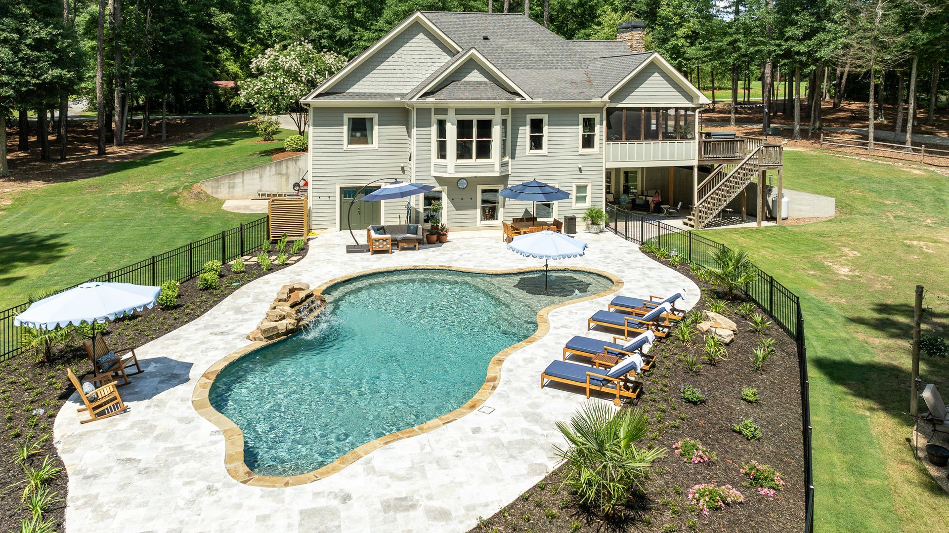 Backyard with kidney-shaped pool, patio loungers, and a two-story house surrounded by trees