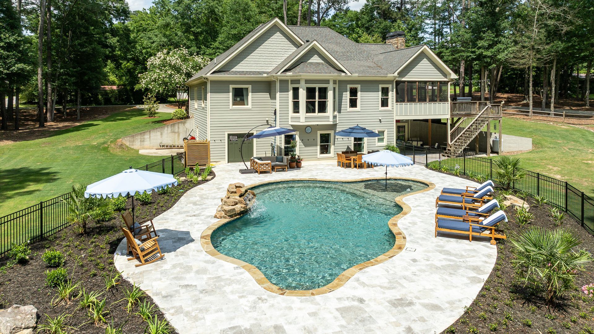 Backyard with kidney-shaped pool, patio chairs, umbrellas, and a two-story house surrounded by trees