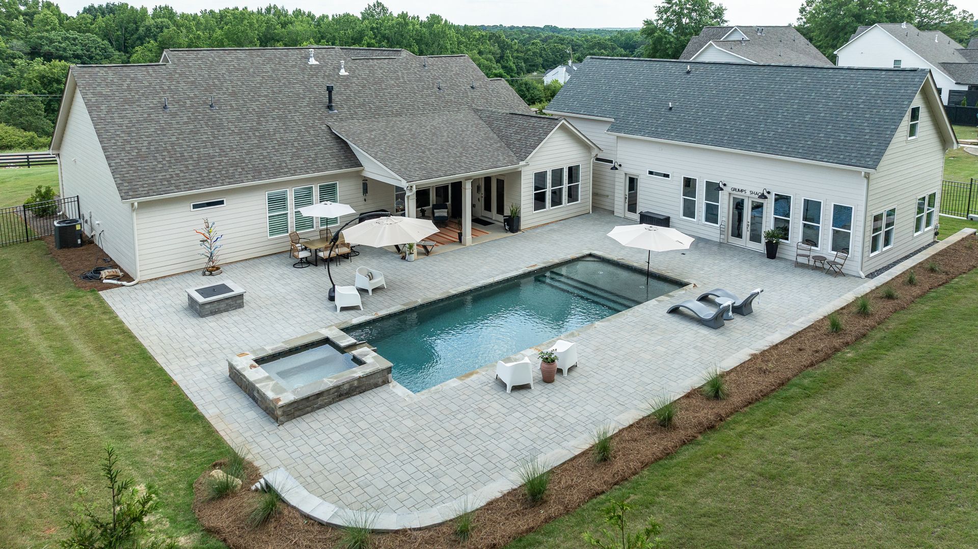 Aerial view of a modern home with a patio, swimming pool, and backyard lounge area