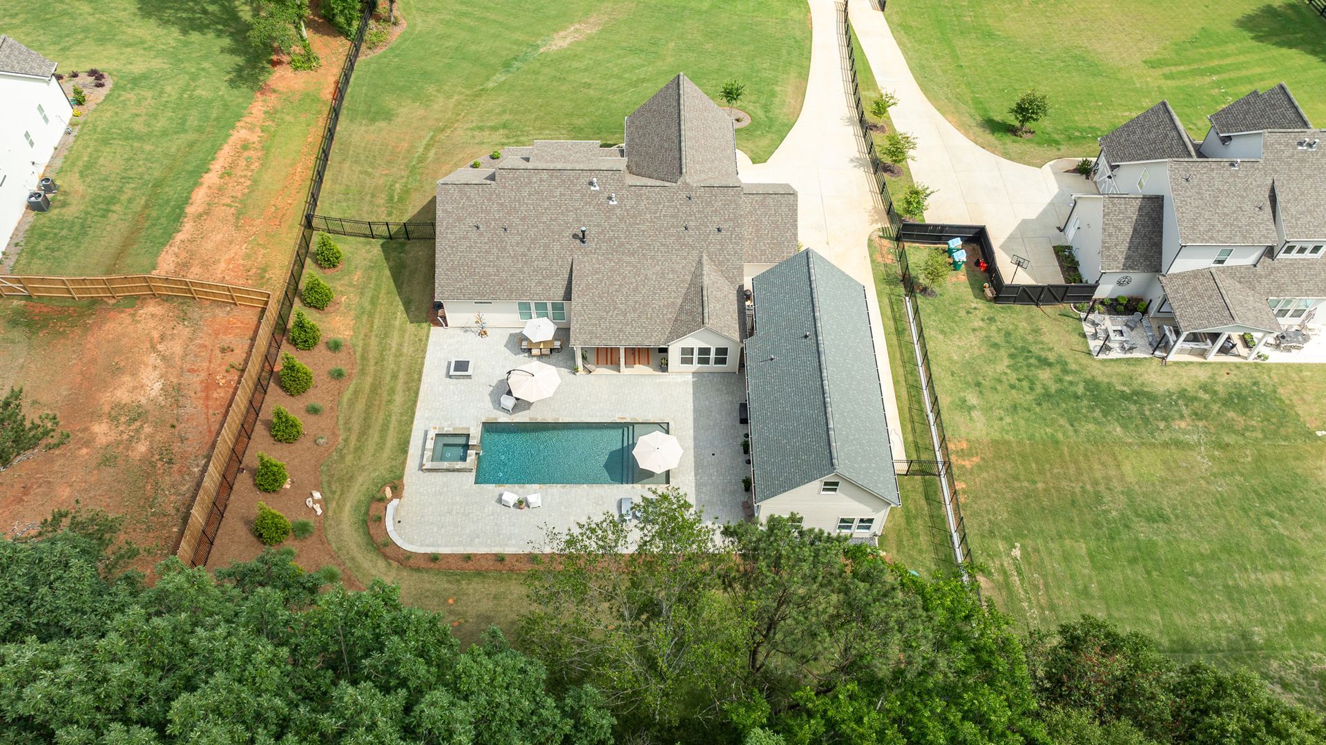 Aerial view of a suburban house with a backyard pool, patio, and surrounding lawn.