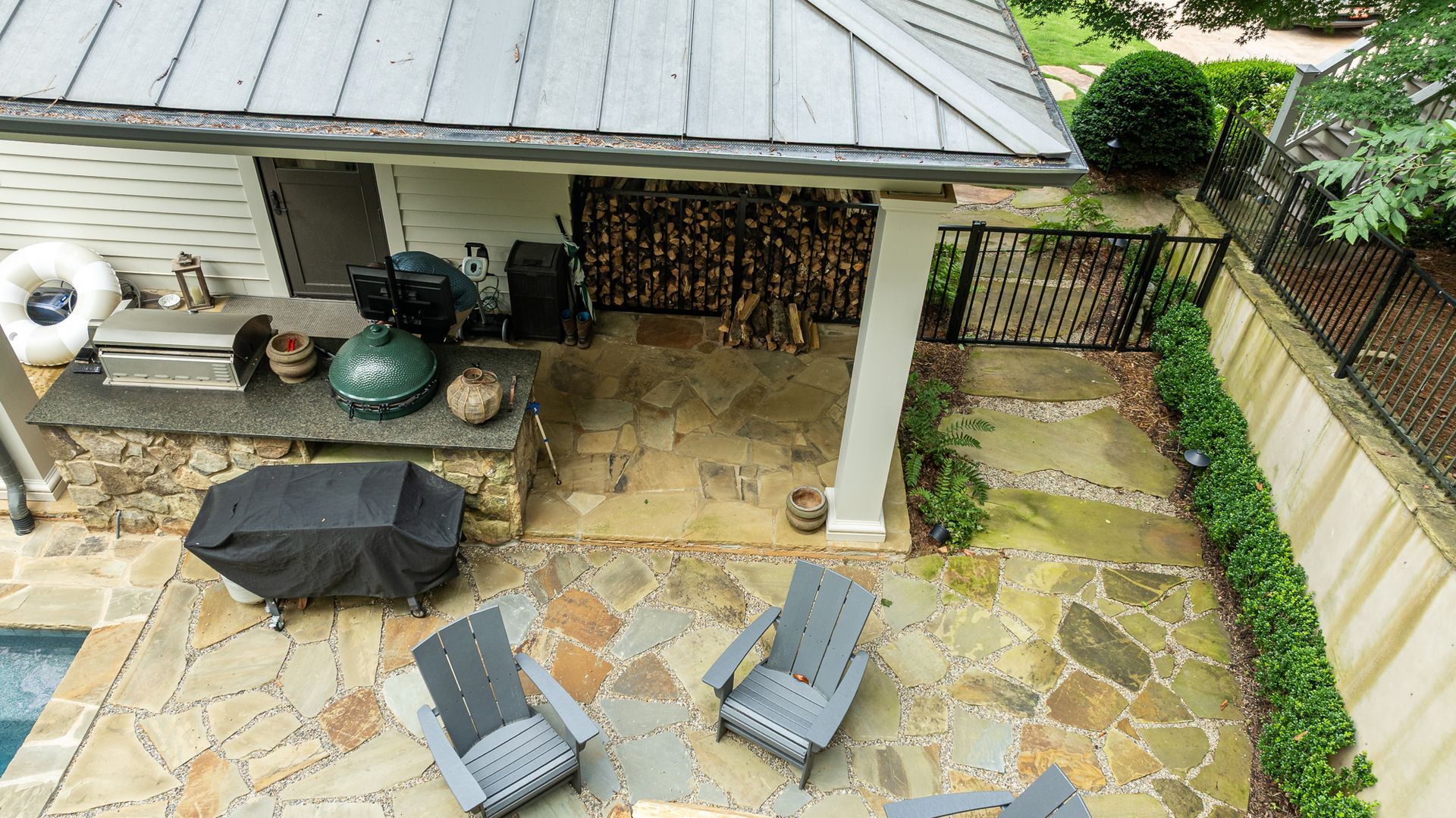 Patio with stone paving, outdoor seating, grill, and wood storage beside a covered porch