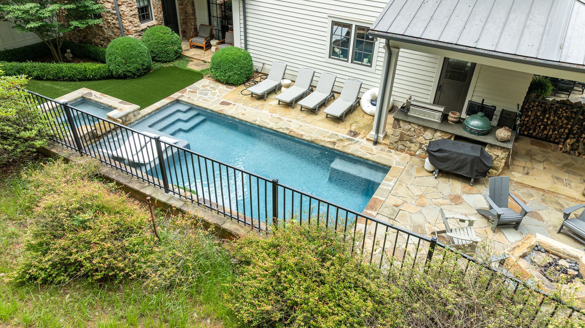 Backyard with a small rectangular pool, patio lounge chairs, and covered seating area beside a house