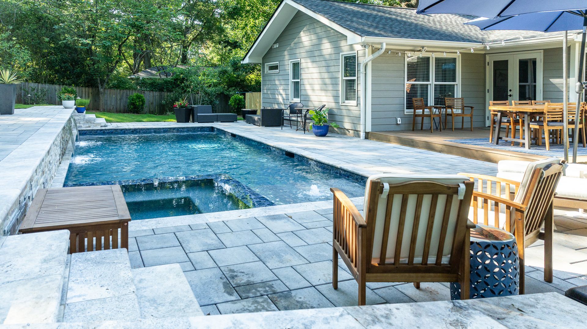 Backyard patio with a swimming pool, lounge chairs, and a house with an outdoor dining area
