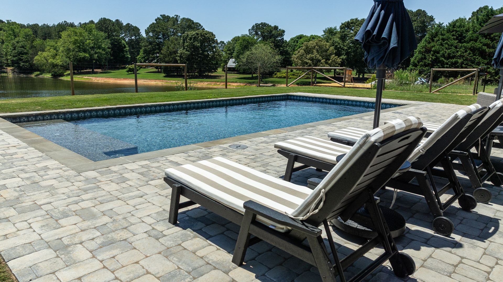 Poolside lounge chairs beside a rectangular swimming pool on a sunny day