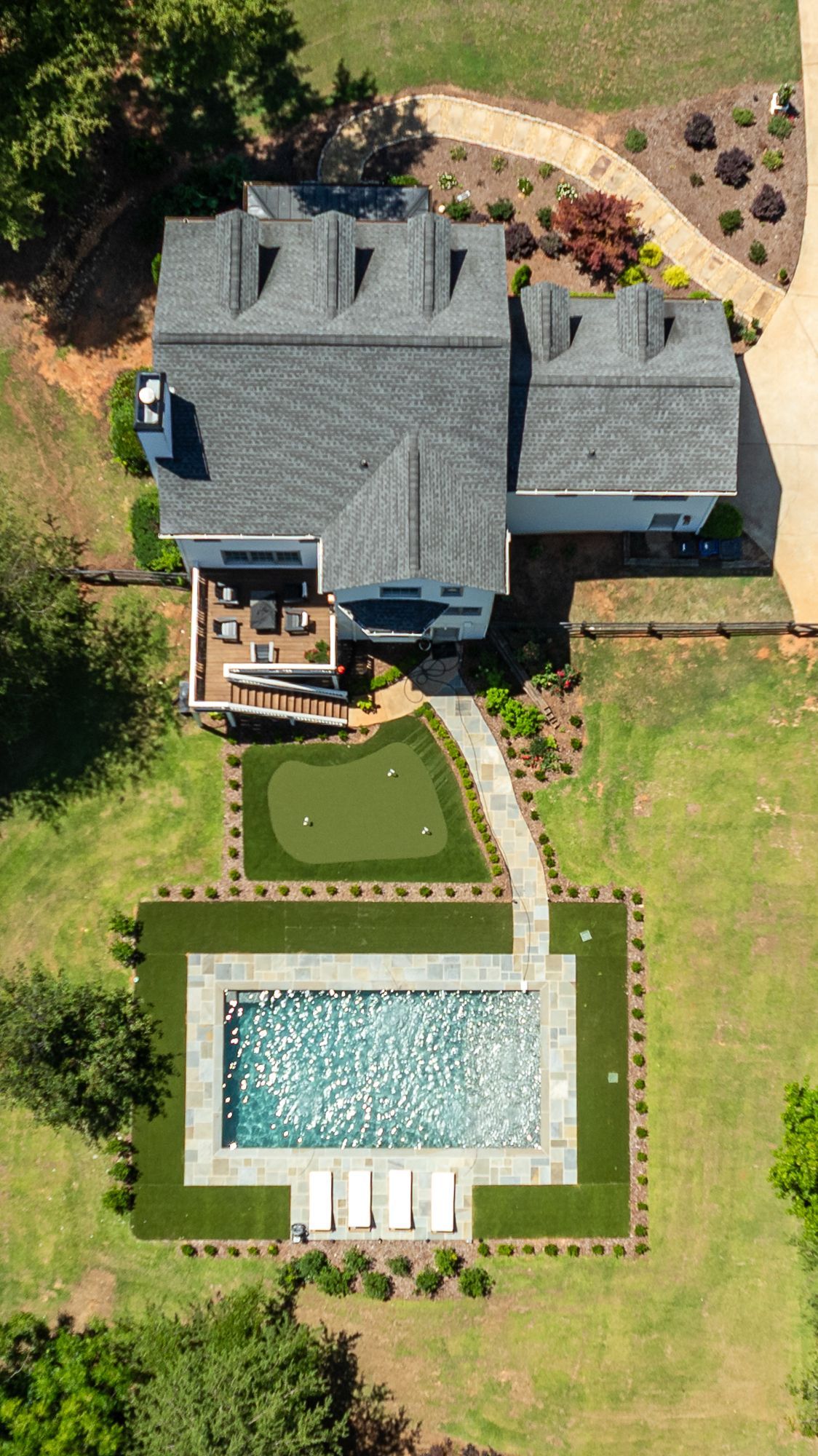 Aerial view of a house with a backyard pool, patio, and manicured lawn.