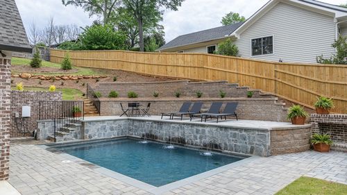 There is a large swimming pool in the backyard of a house.