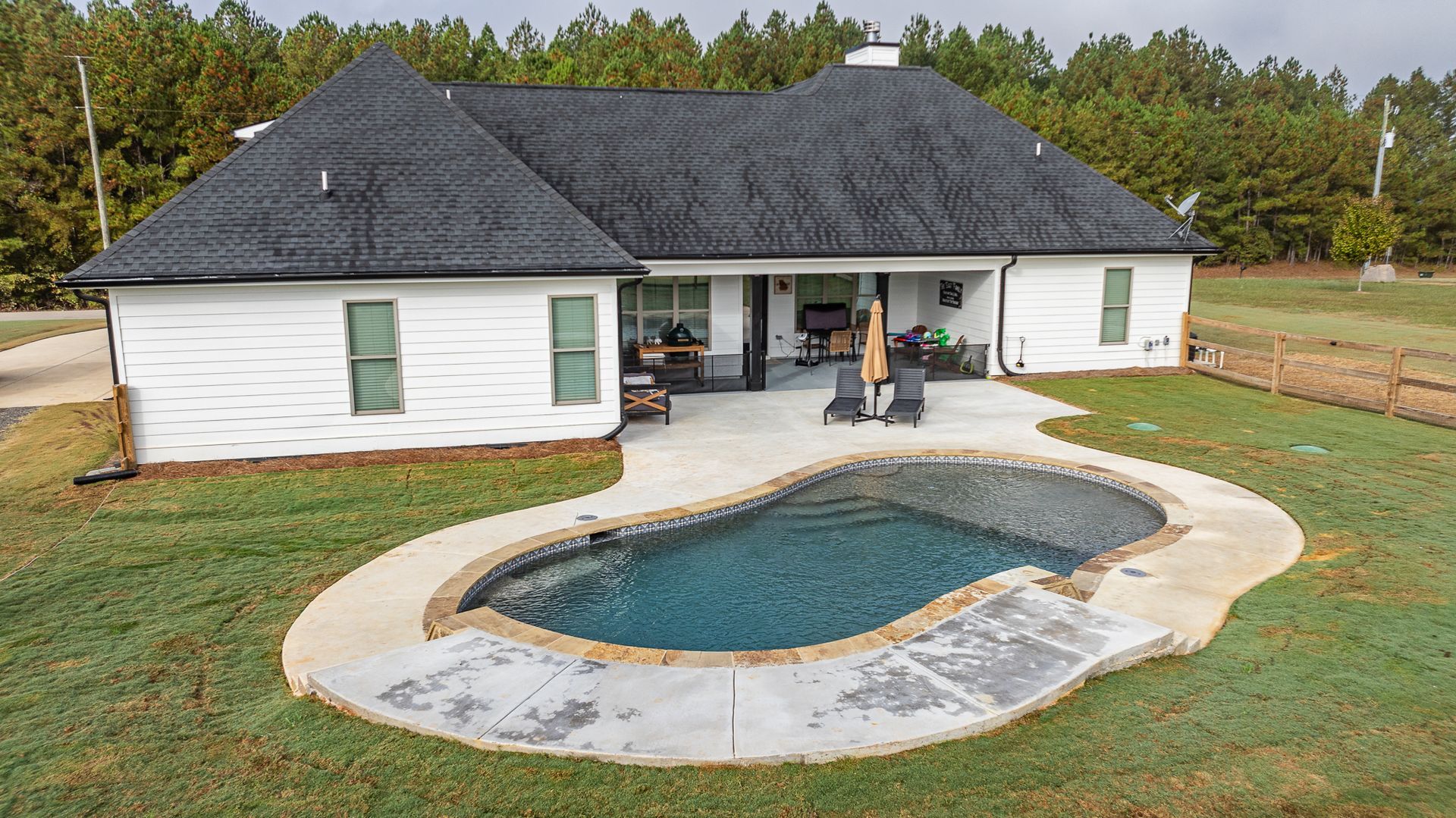 A white house with a large swimming pool in front of it.