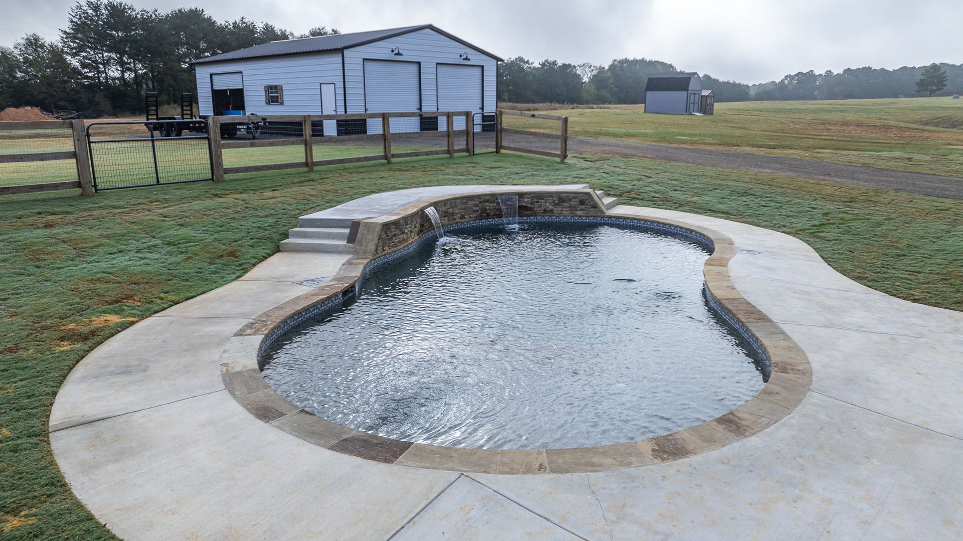 A large swimming pool is in the middle of a grassy field.
