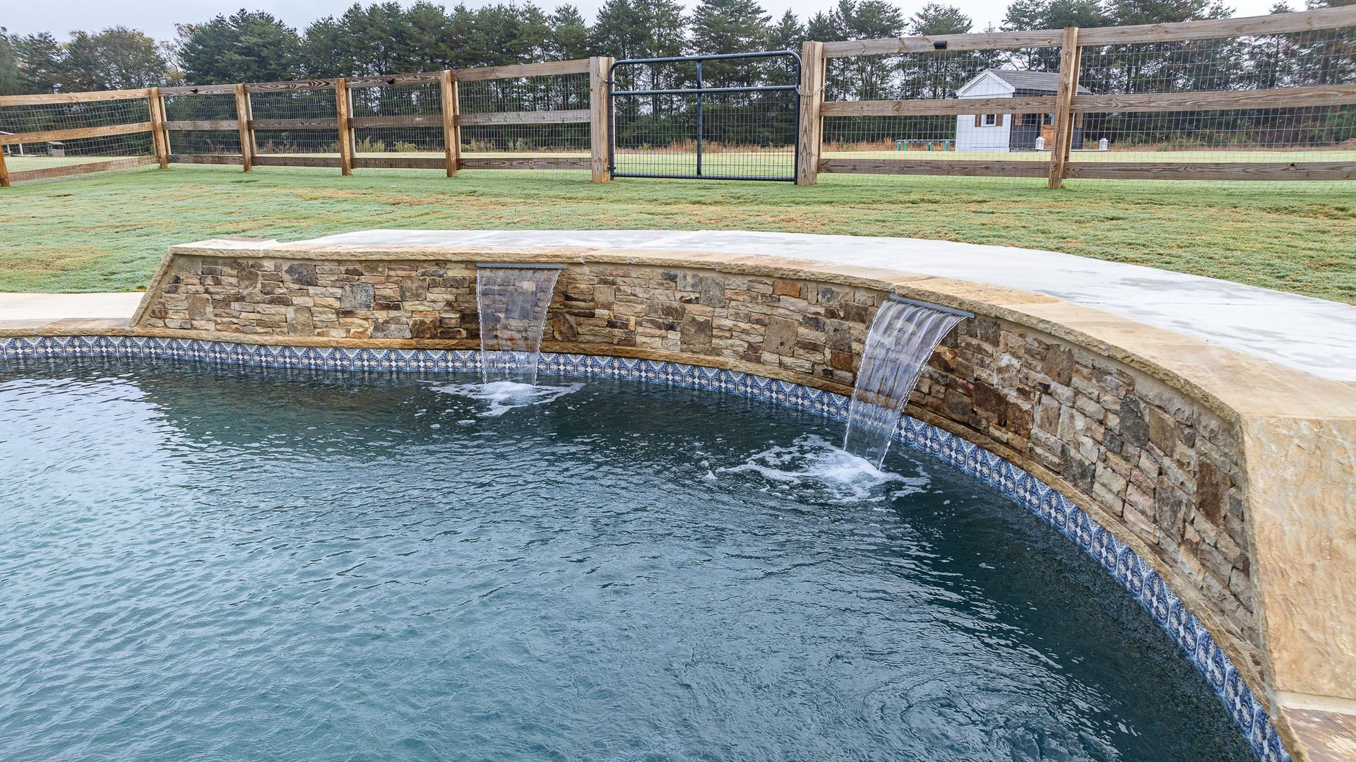 A swimming pool with a wooden fence in the background