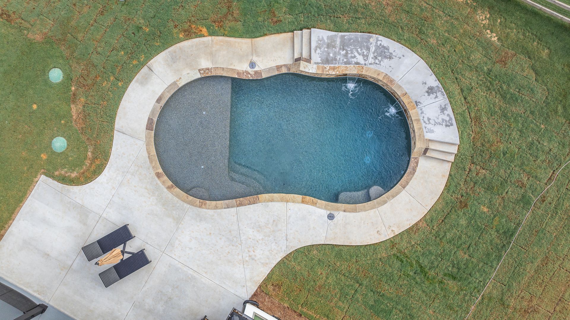 An aerial view of a large swimming pool in a backyard.