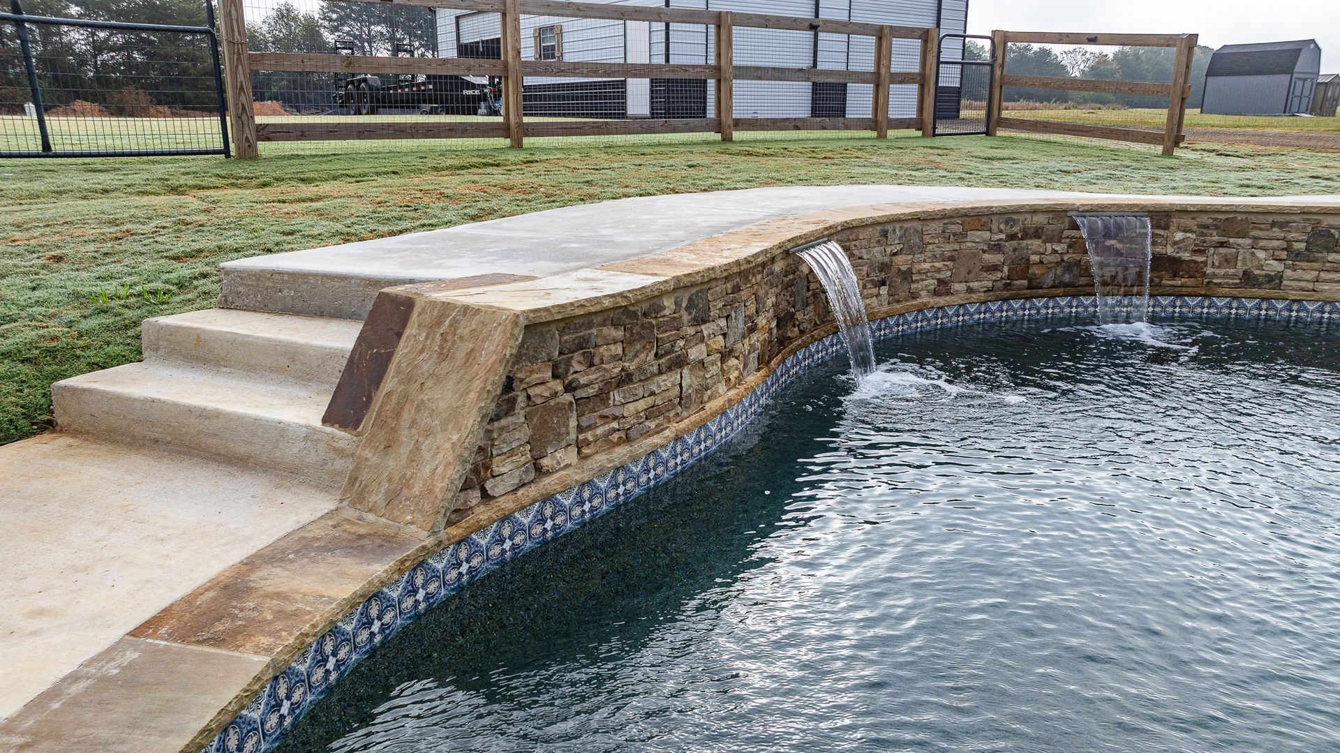 A swimming pool with stairs leading to it and a waterfall.