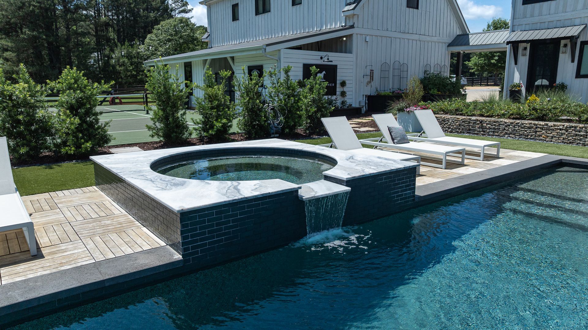 Backyard pool with spa, lounge chairs, and a white house in the background