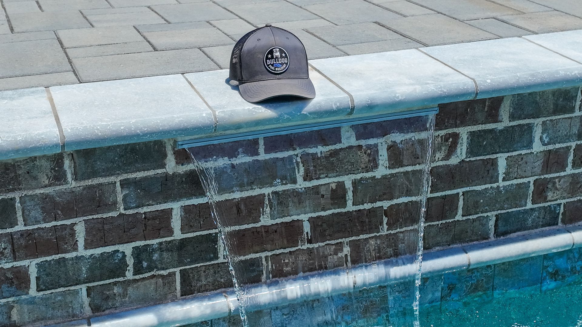 Gray cap resting on a brick ledge beside a swimming pool