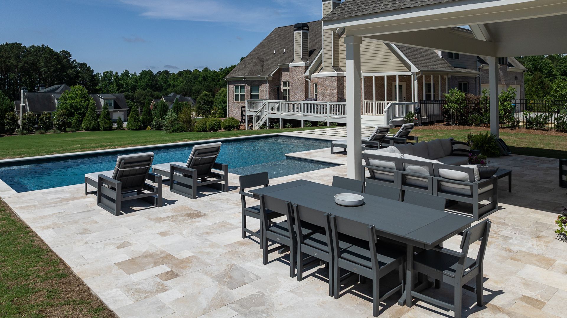 Backyard pool patio with outdoor dining and lounge chairs beside a clubhouse-like building