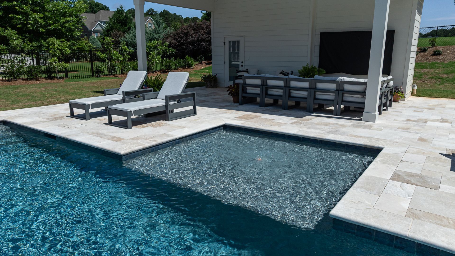 Poolside patio with lounge chairs and an outdoor dining area beside a turquoise swimming pool