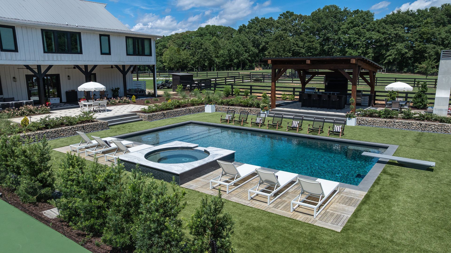 Outdoor resort pool with hot tub, lounge chairs, and a shaded pavilion beside a building