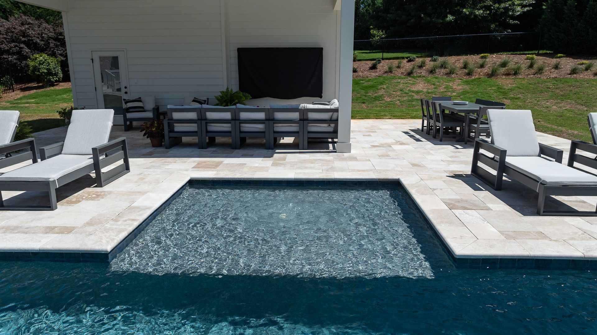 Backyard pool with a raised spa, lounge chairs, and a covered patio seating area