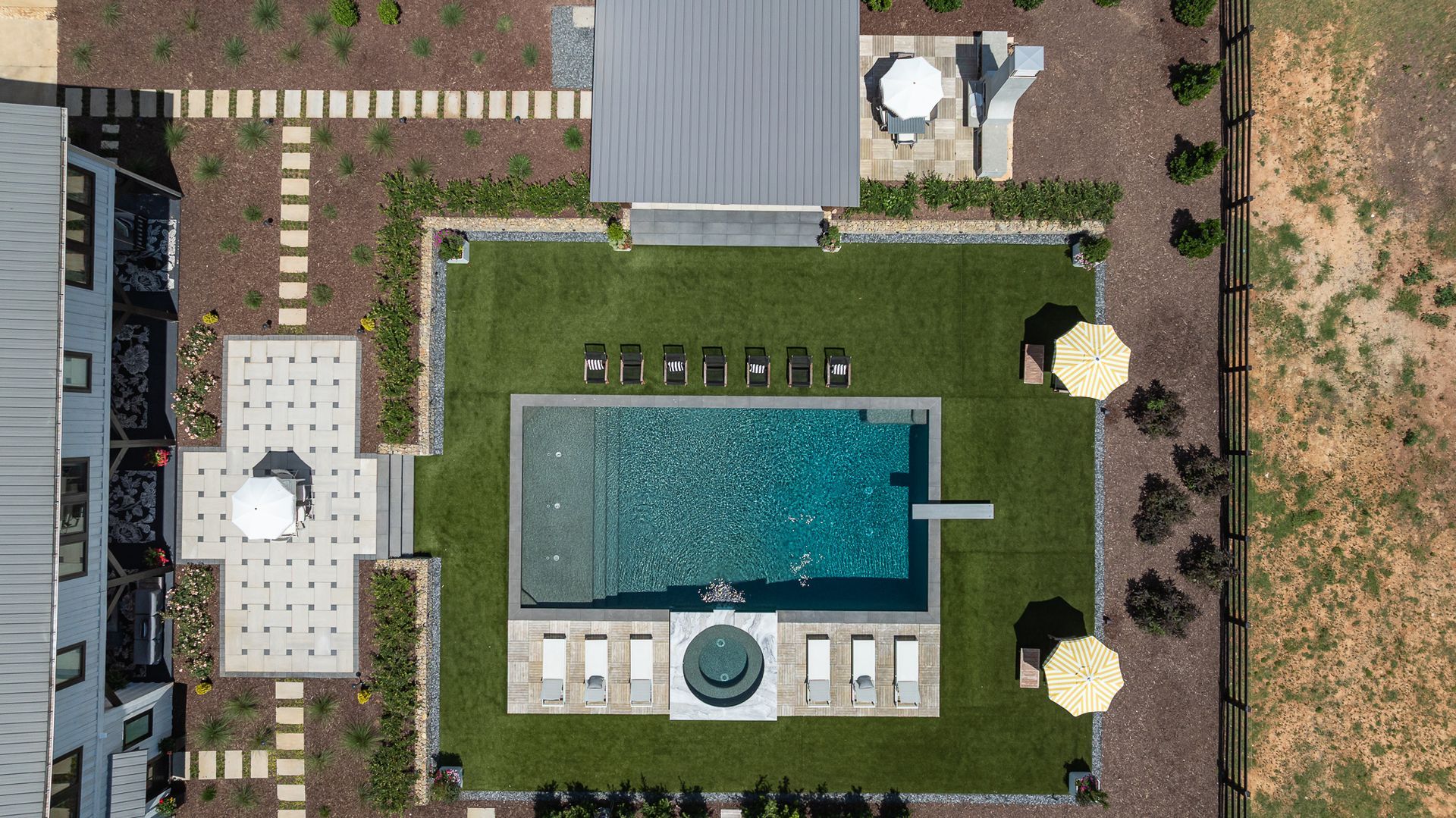 Aerial view of a landscaped courtyard with a central pool, lounge chairs, and pathways around a building