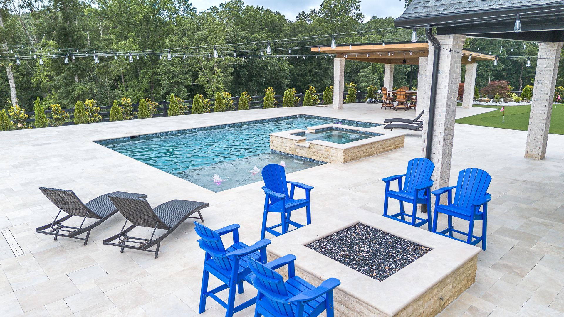 Outdoor pool and patio with blue chairs, fire pit, and lounge chairs.