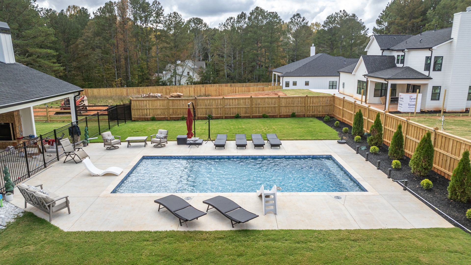 There is a large swimming pool in the backyard of a house.