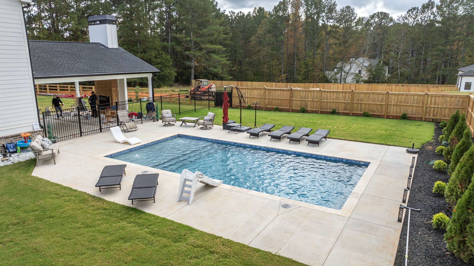 There is a large swimming pool in the backyard of a house.