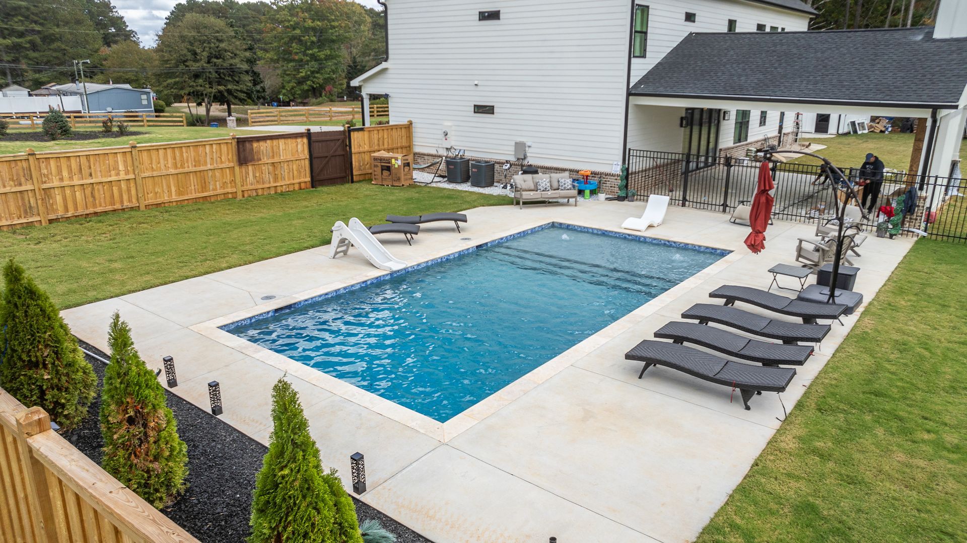 There is a large swimming pool in the backyard of a house.