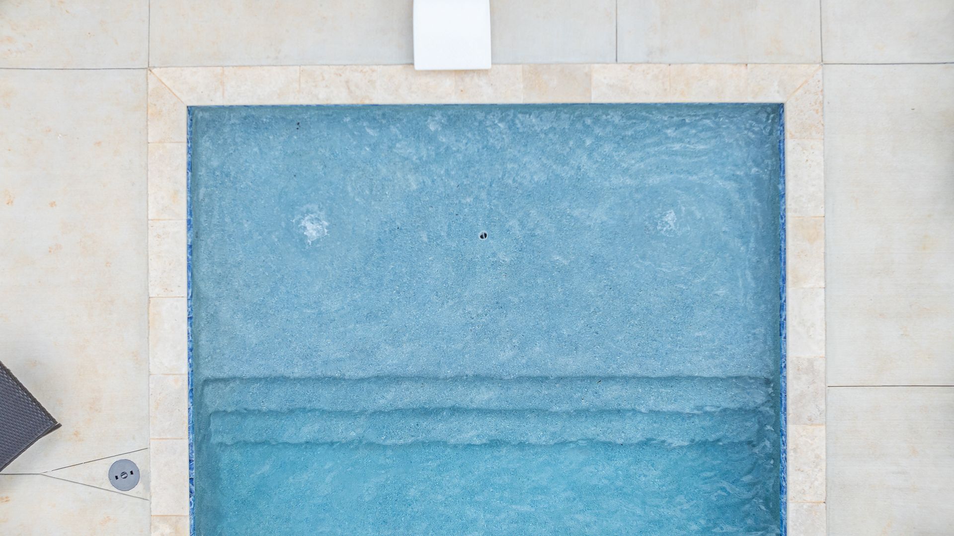 An aerial view of a swimming pool with blue water and steps.