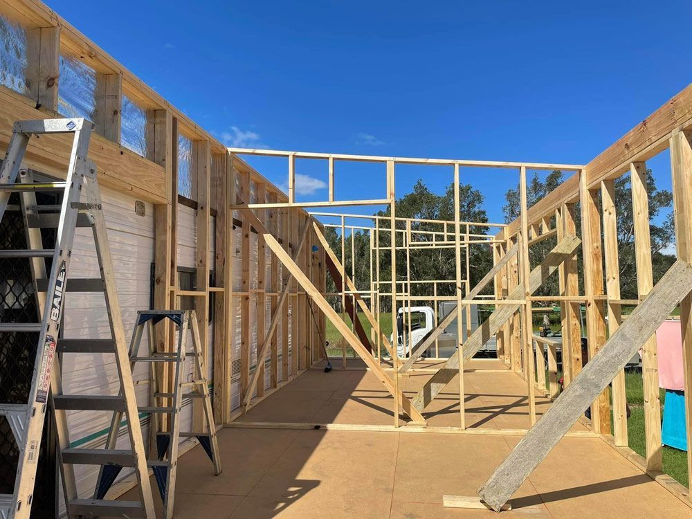 A Wooden House Is Being Built with A Ladder and Stairs — J’s Concreting & Carpentry in Laurieton, NSW