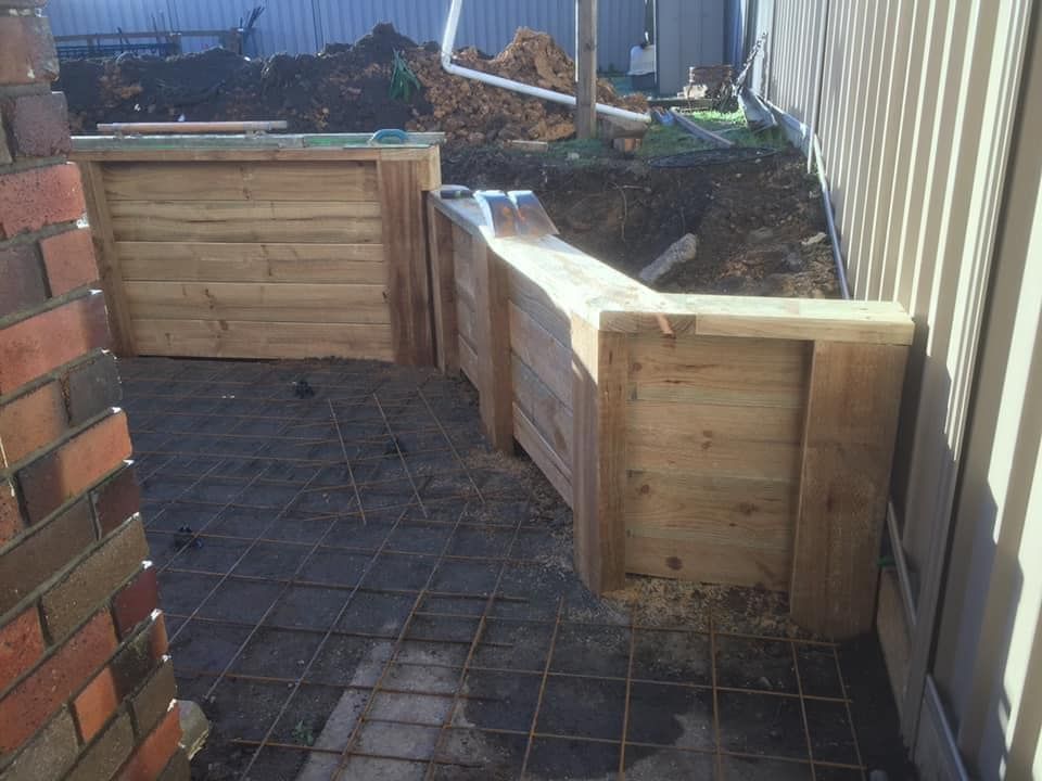A Wooden Wall Is Being Built Next to A Brick Wall — J’s Concreting & Carpentry in Laurieton, NSW