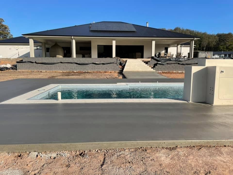 A Large House with A Swimming Pool in Front of It — J’s Concreting & Carpentry in Laurieton, NSW