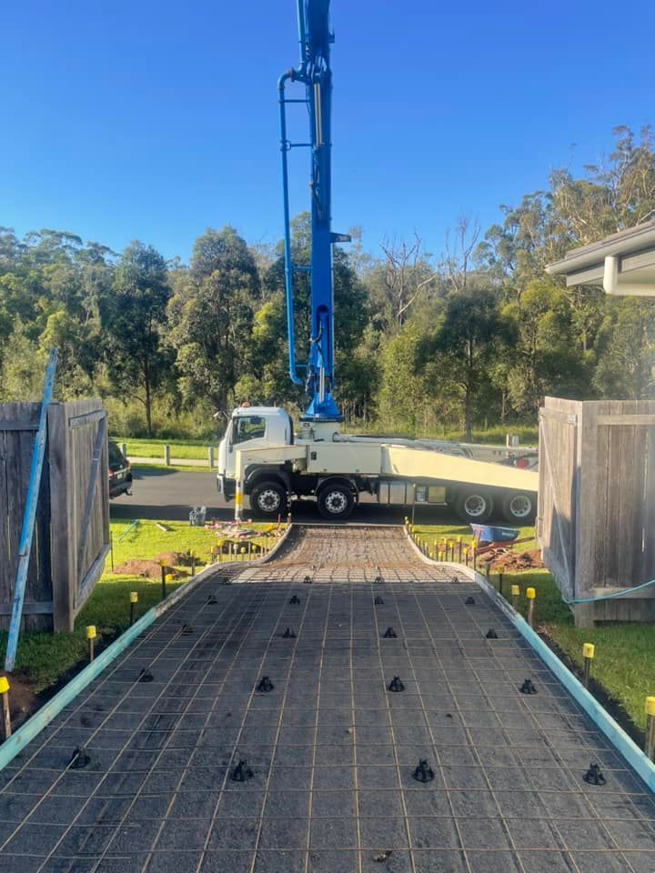 A Truck with A Crane on The Back of It Is Driving Down a Driveway — J’s Concreting & Carpentry in Bonny Hills, NSW