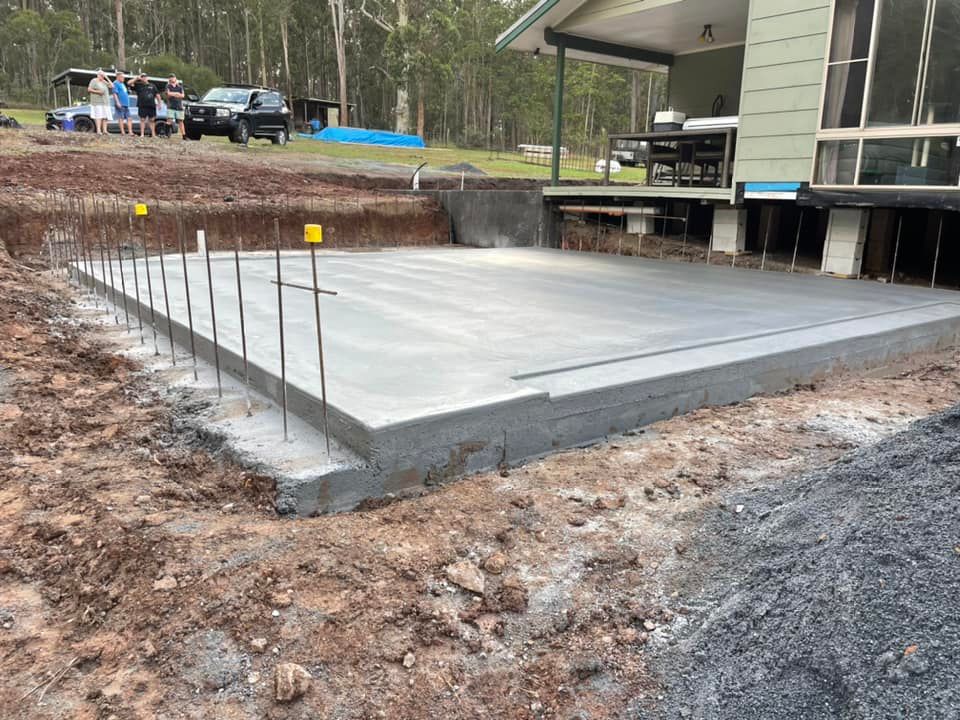 A Concrete Slab Is Being Built in Front of A House — J’s Concreting & Carpentry in Lake Cathie, NSW