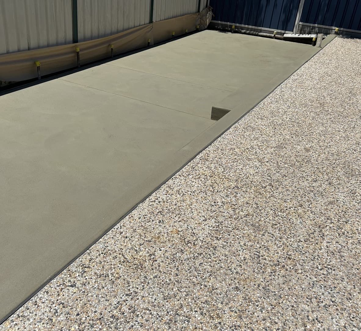 A Concrete Driveway with A Fence in The Background and A House in The Background — J’s Concreting & Carpentry in Kew, NSW