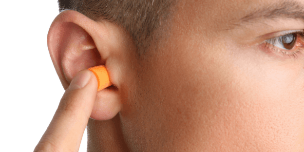 man putting in earplugs to prevent hearing loss
