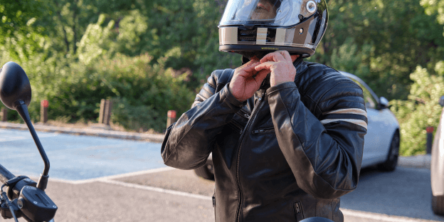 man putting on motorcycle helmet while wearing noise defenders for motorcyclists.