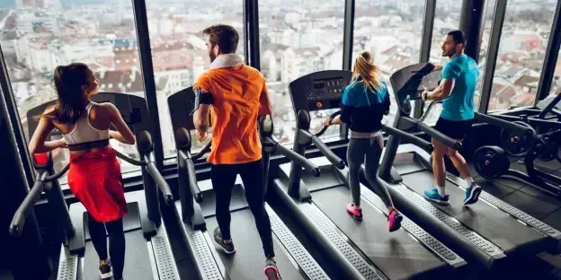 group of people running on treadmills at a gym